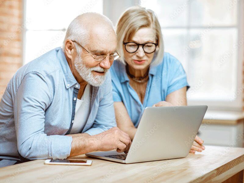 An elderly couple playing on the computer