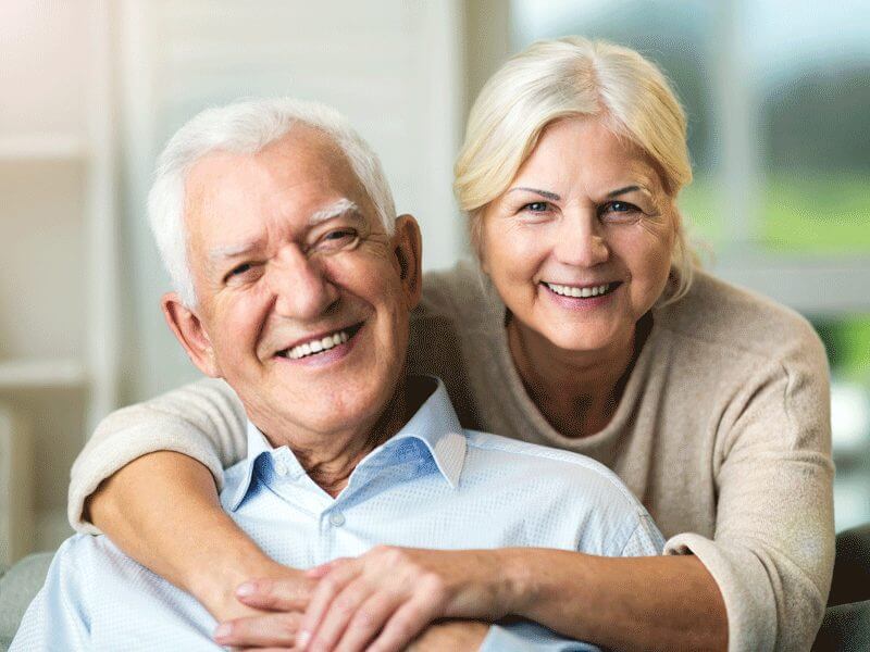 Old couple smiling and looking at the camera