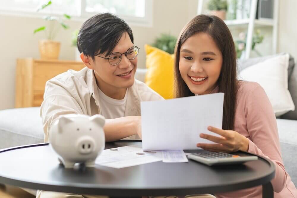 Young smiling couple planning their estate with paperwork and calculator on table