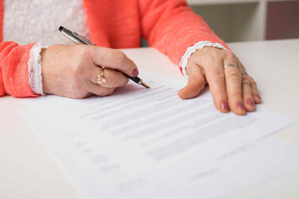 Senior woman signing papers for estate plan