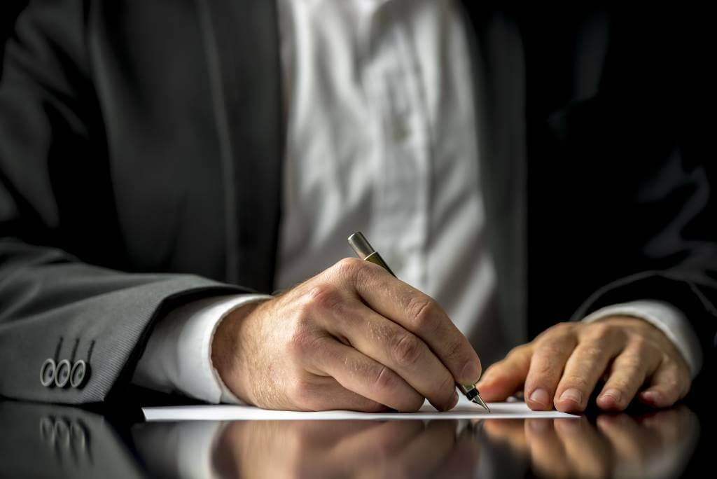 A Man Signing A Document