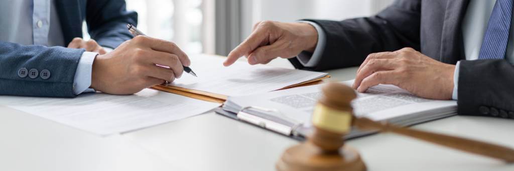 Two Men Signing Documents Laid Out On A Table