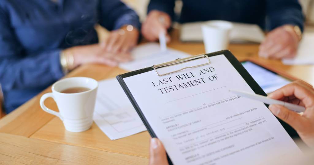 A lawyer holding a will on a clipboard while sitting in front of a couple.