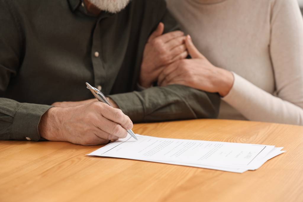 A senior couple signing paperwork.