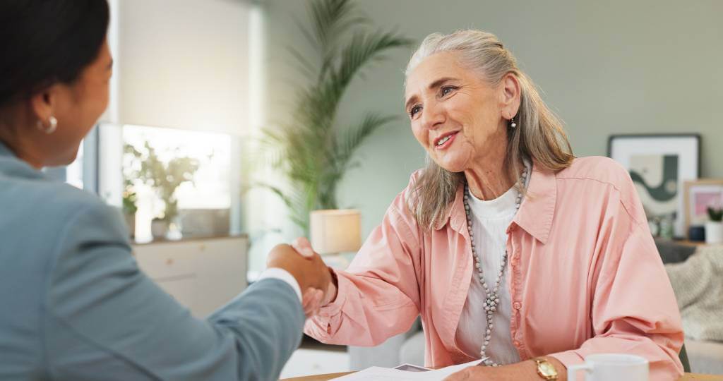 A senior woman shaking hands with a trust lawyer.